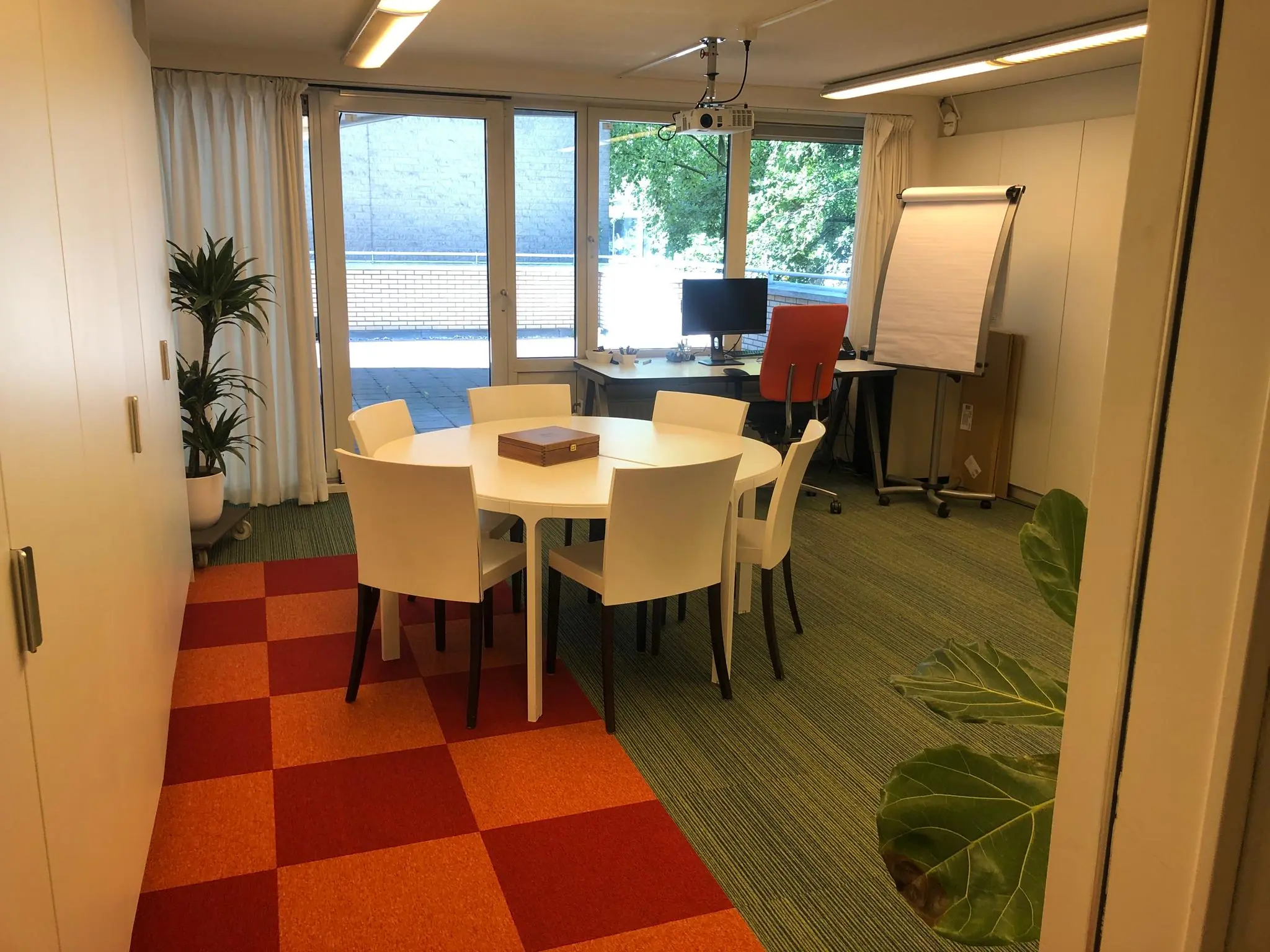 Vergaderruimte aan de Prins Hendrikkade met een ronde tafel, bureaustoel, flip-over en zicht op een buitenruimte.